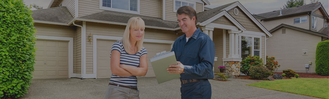 Image of a male Lennox technician showing information to a female customer on a clipboard outside of a house