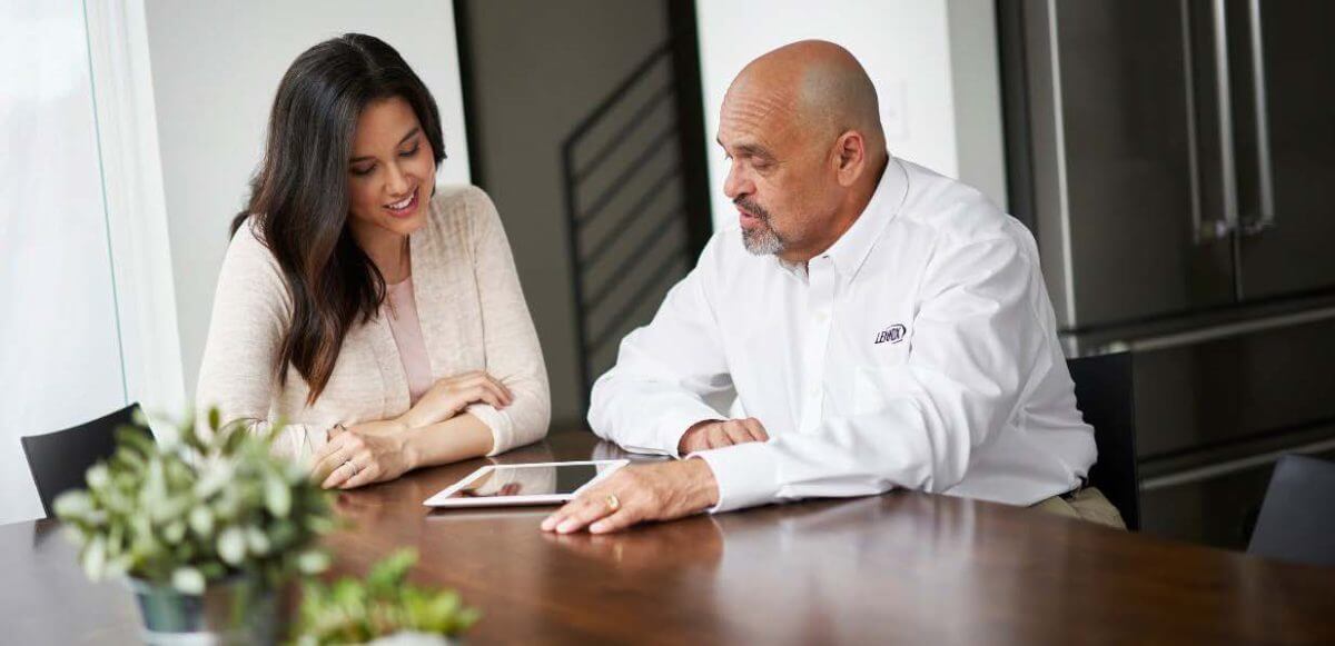 Picture of two people sitting at a table using a tablet.